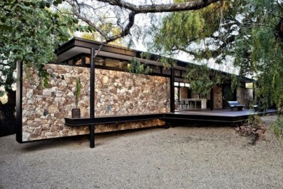Moderna casa de campo con estructura de acero y muros de piedra que parecen flotar