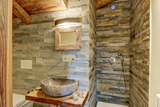 Cuarto de baño con baldosas de piedra rectangulares y lavabo de piedra