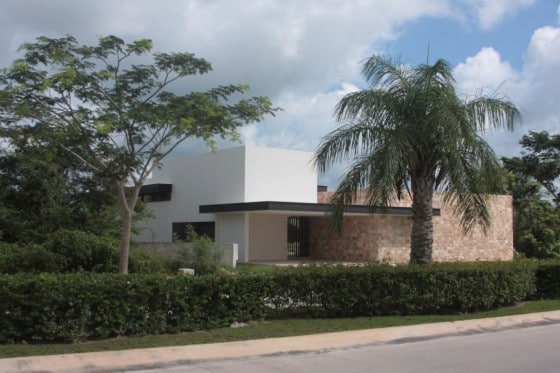 Fachada de casa en forma de L con pared de piedra