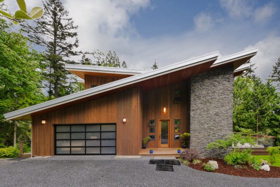 Moderno diseño de casa con techos altos e inclinados, fachada enchapada con madera y piedra