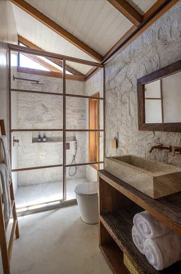 Diseño de cuarto de baño estilo rústico y moderno de una casa de campo, paredes de piedra y techo inclinado